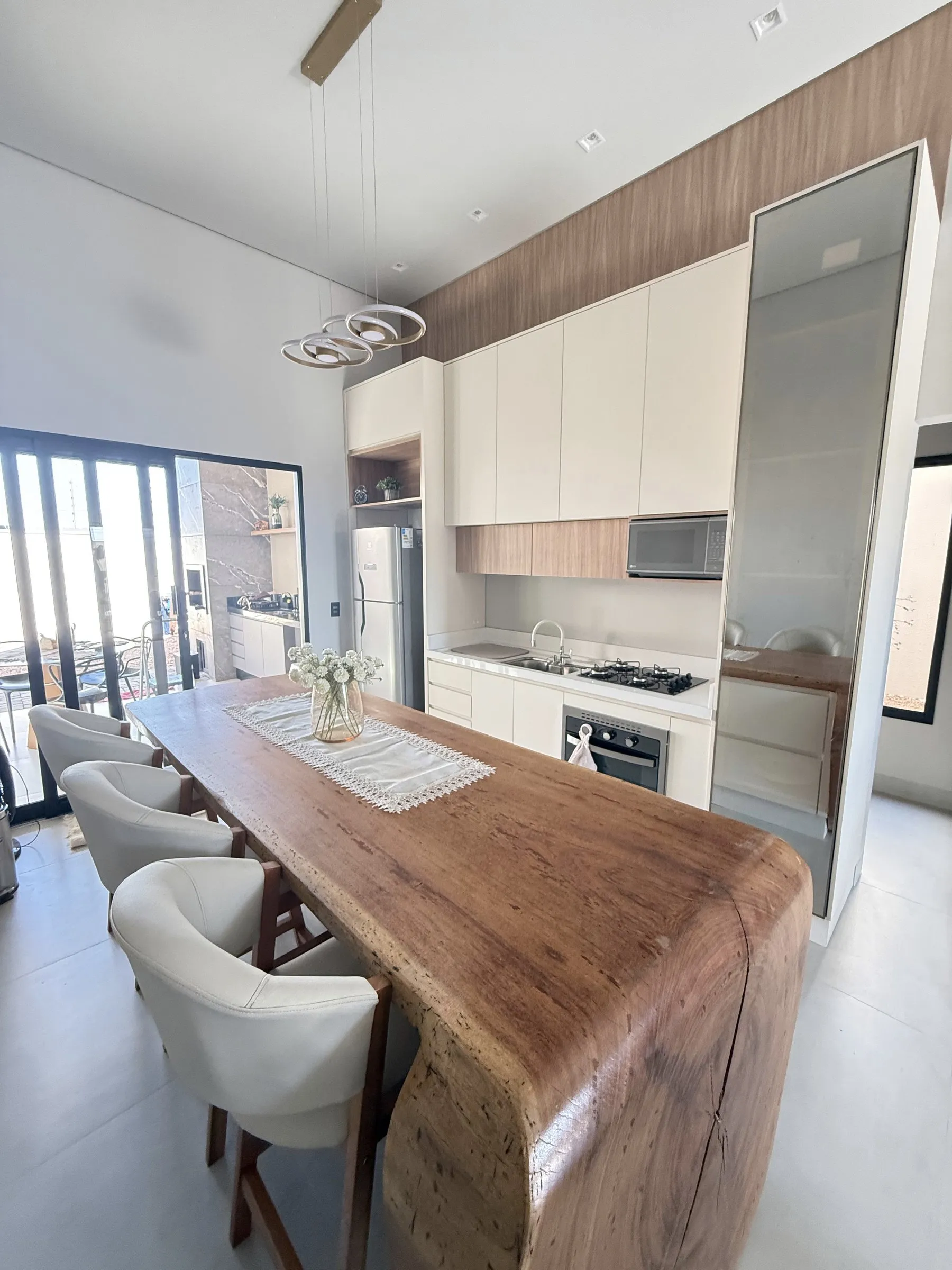 Cozinha clássica planejada em tons claros, com ilha em madeira maciça e torre com porta de vidro reflecta